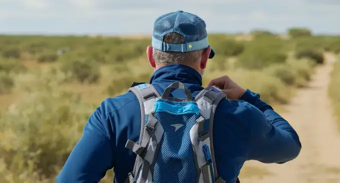 =An older marathon runner preparing their hydration strategy during outdoor training.