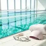 Photorealistic wide shot of an indoor pool lane with safety gear, representing a beginner swim workout in a clean, modern facility.
