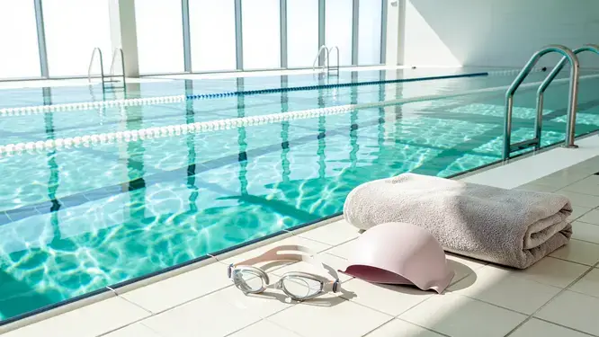 Photorealistic wide shot of an indoor pool lane with safety gear, representing a beginner swim workout in a clean, modern facility.